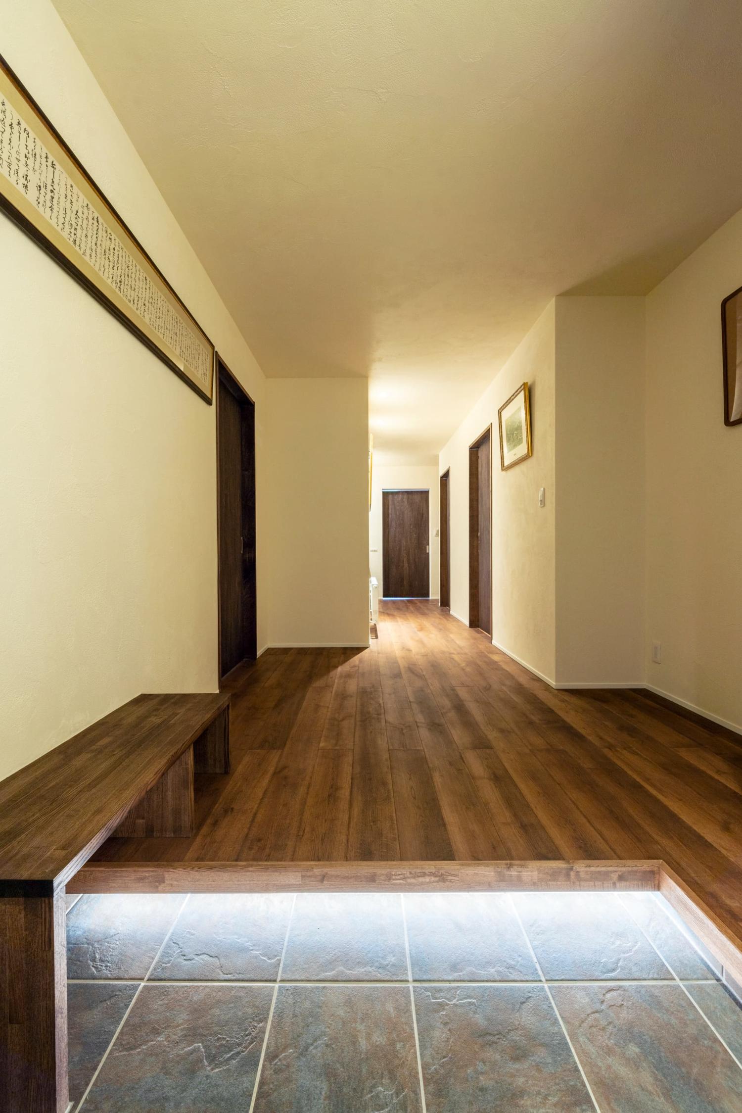 上がり框に設置された間接照明が柔らかく足元を照らす玄関ホール