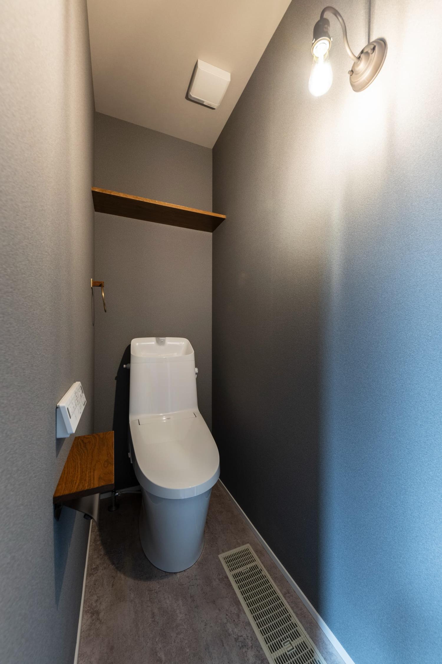 グレーのベースクロスに淡いネイビーのアクセントクロスを合わせたトイレ