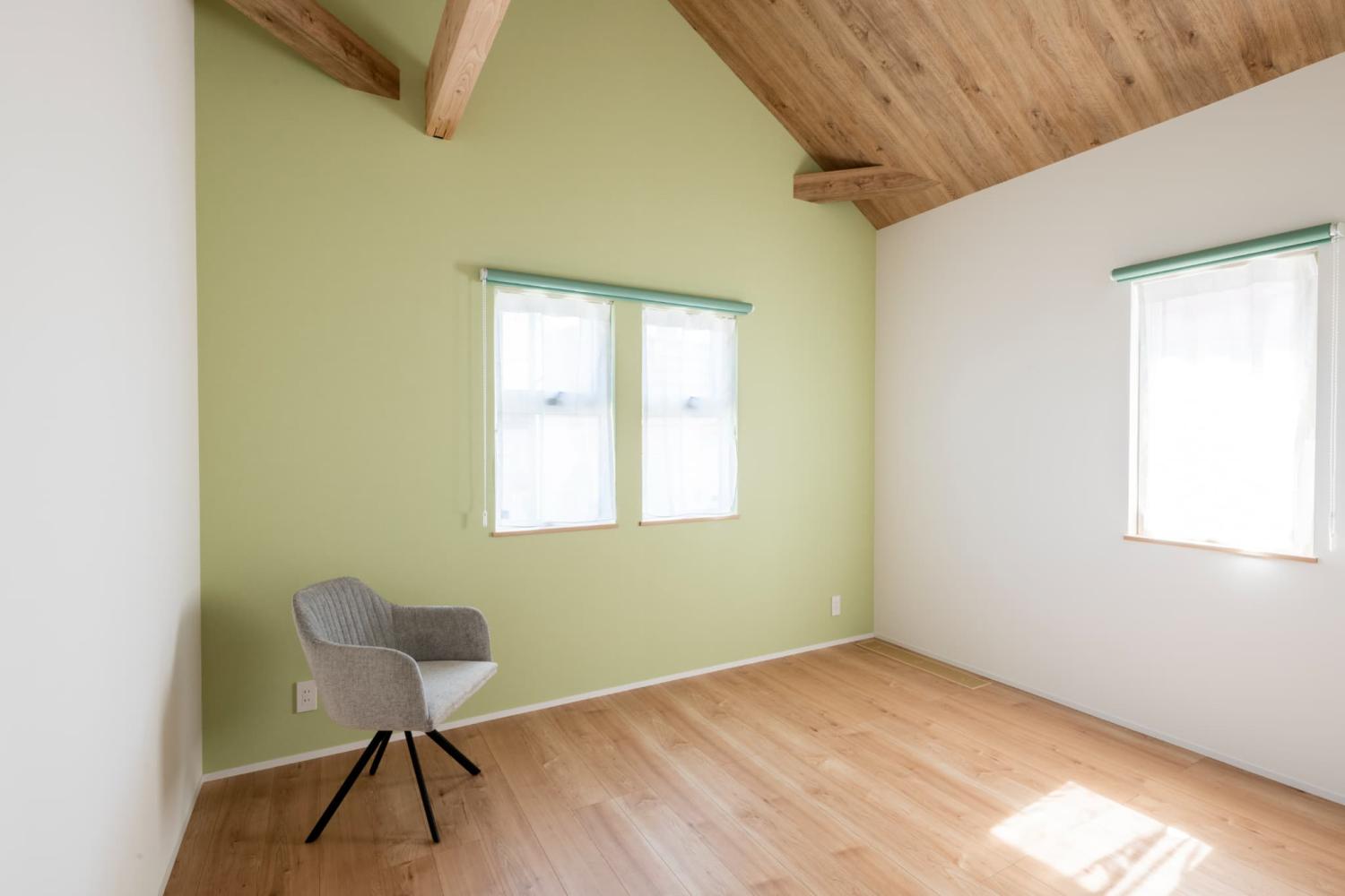 淡いグリーンの壁紙や温かみのある木目を採用した寝室